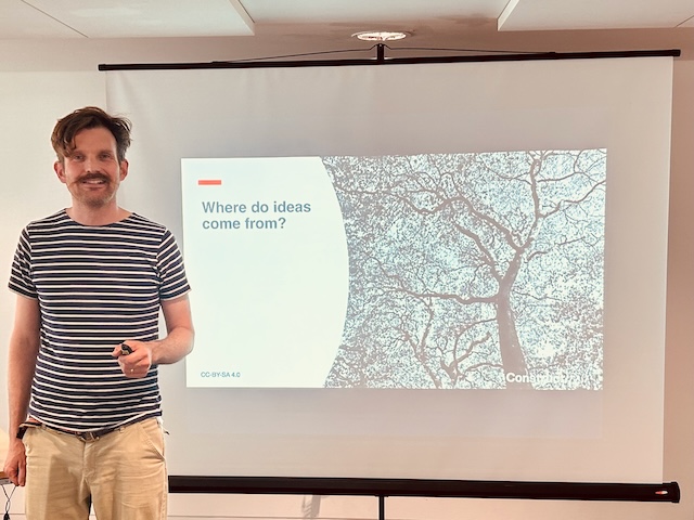 Photo of Oliver Broadbent delivering the How to have ideas workshop - standing in front of a slide that says where do ideas come from